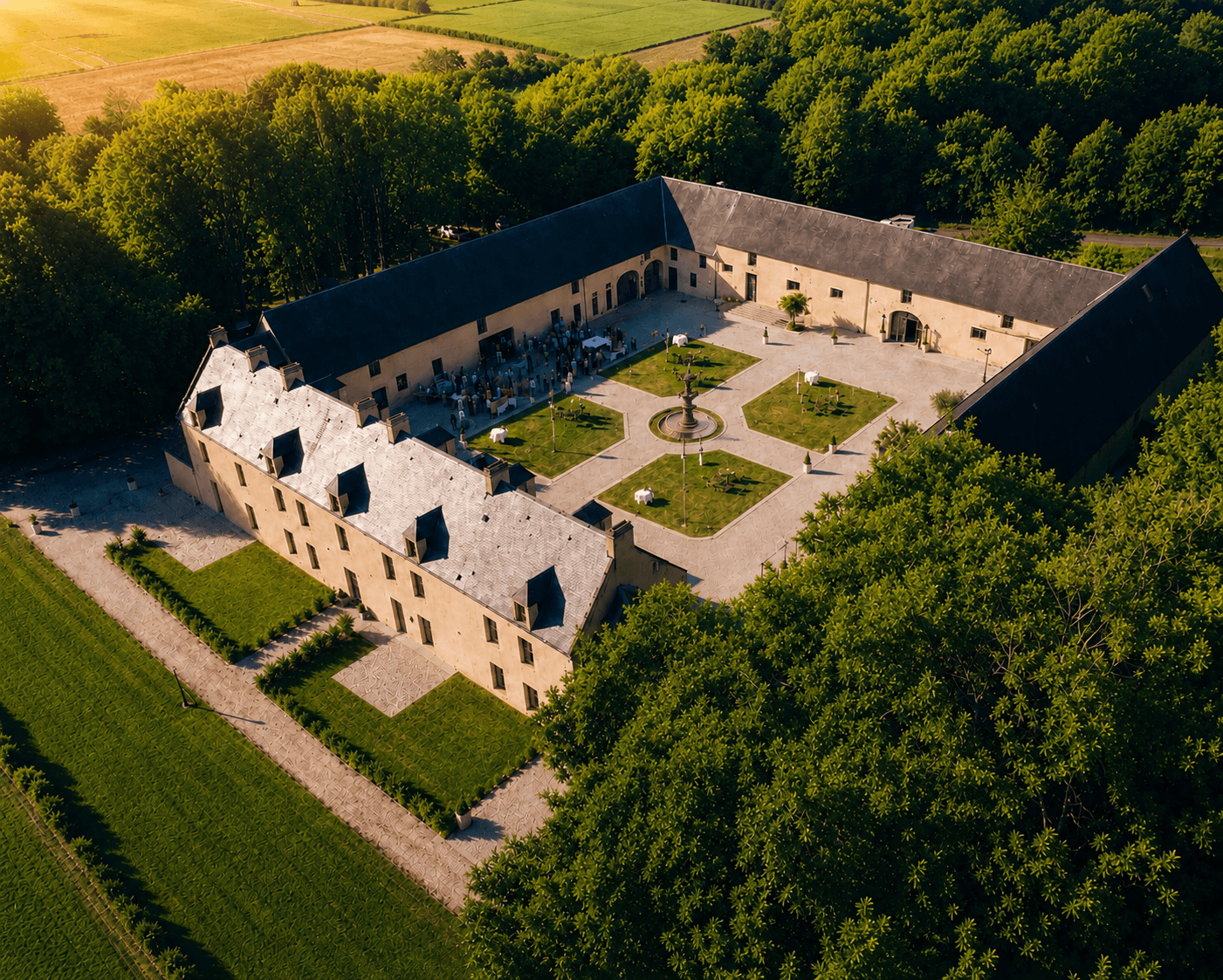 Vue aérienne du Domaine de la Cour des Lys à l'heure dorée — un domaine de mariage en Calvados, cocktail dans la Cour d'Honneur