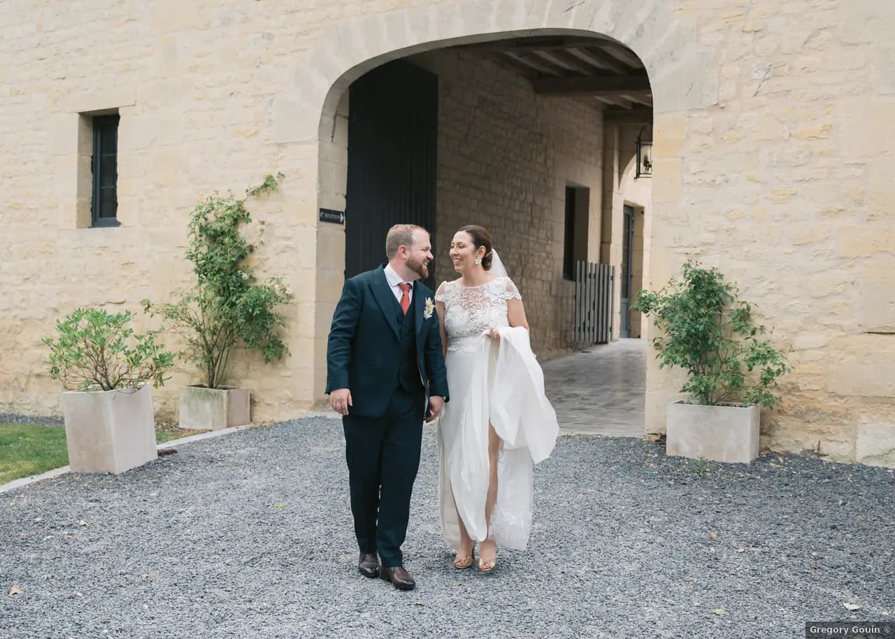 Lise et Antoine sous le porche en pierre du Domaine de la Cour des Lys le jour de leur mariage — mariage d'été en Normandie, 8 juillet 2023