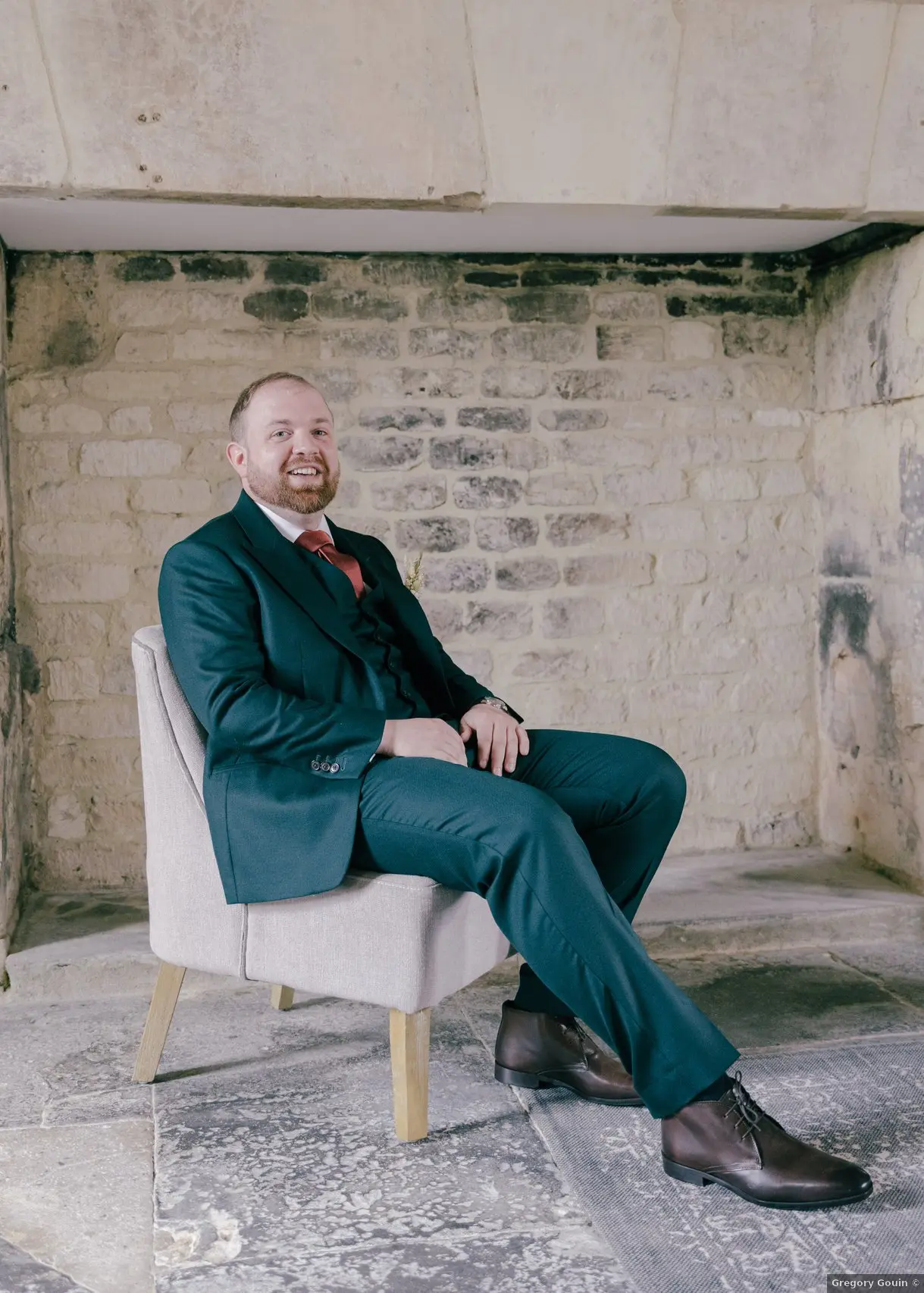 Portrait marié mariage Calvados — Antoine en costume trois pièces vert sapin et cravate dans la cour pavée du Domaine de la Cour des Lys