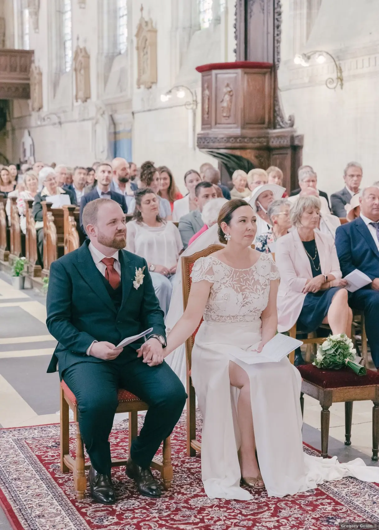 Cérémonie religieuse mariage Calvados — Lise et Antoine face à l'autel d'une église à Caen, invités présents en arrière-plan