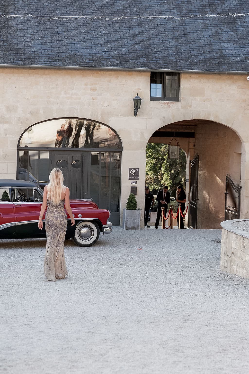 Arrivée d'une invitée en robe longue devant l'entrée du Domaine de la Cour des Lys, voiture ancienne et tapis d'accueil — Festival de la Mode de Caen