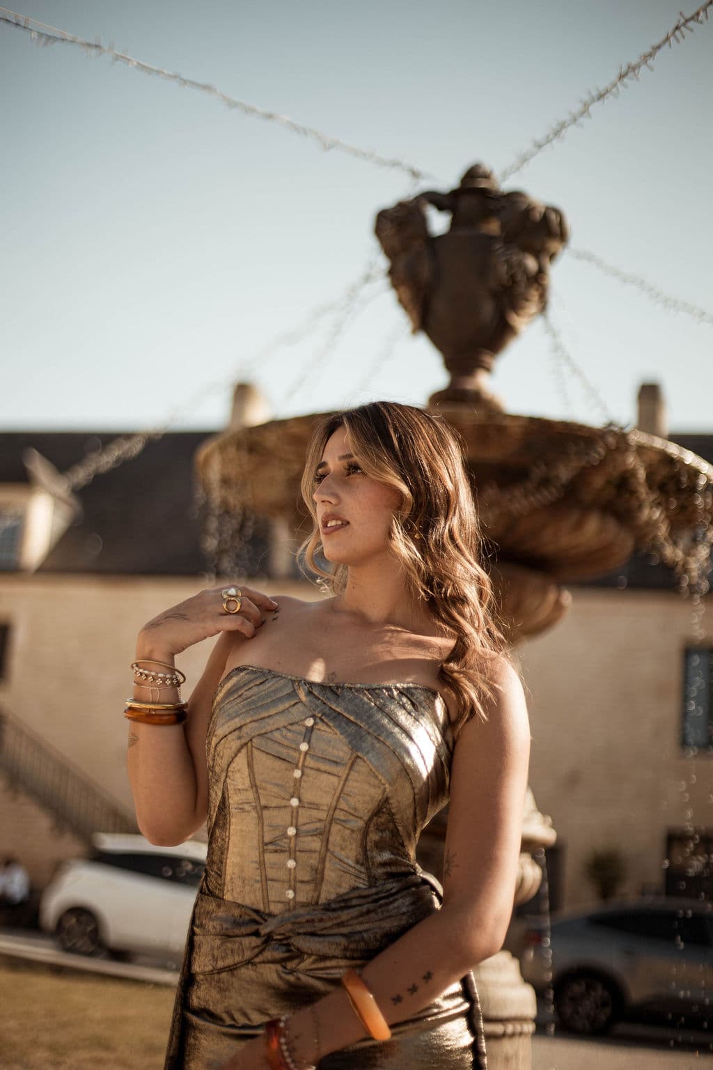 Mannequin en robe dorée devant la fontaine du Domaine de la Cour des Lys à l'heure dorée — Festival de la Mode de Caen