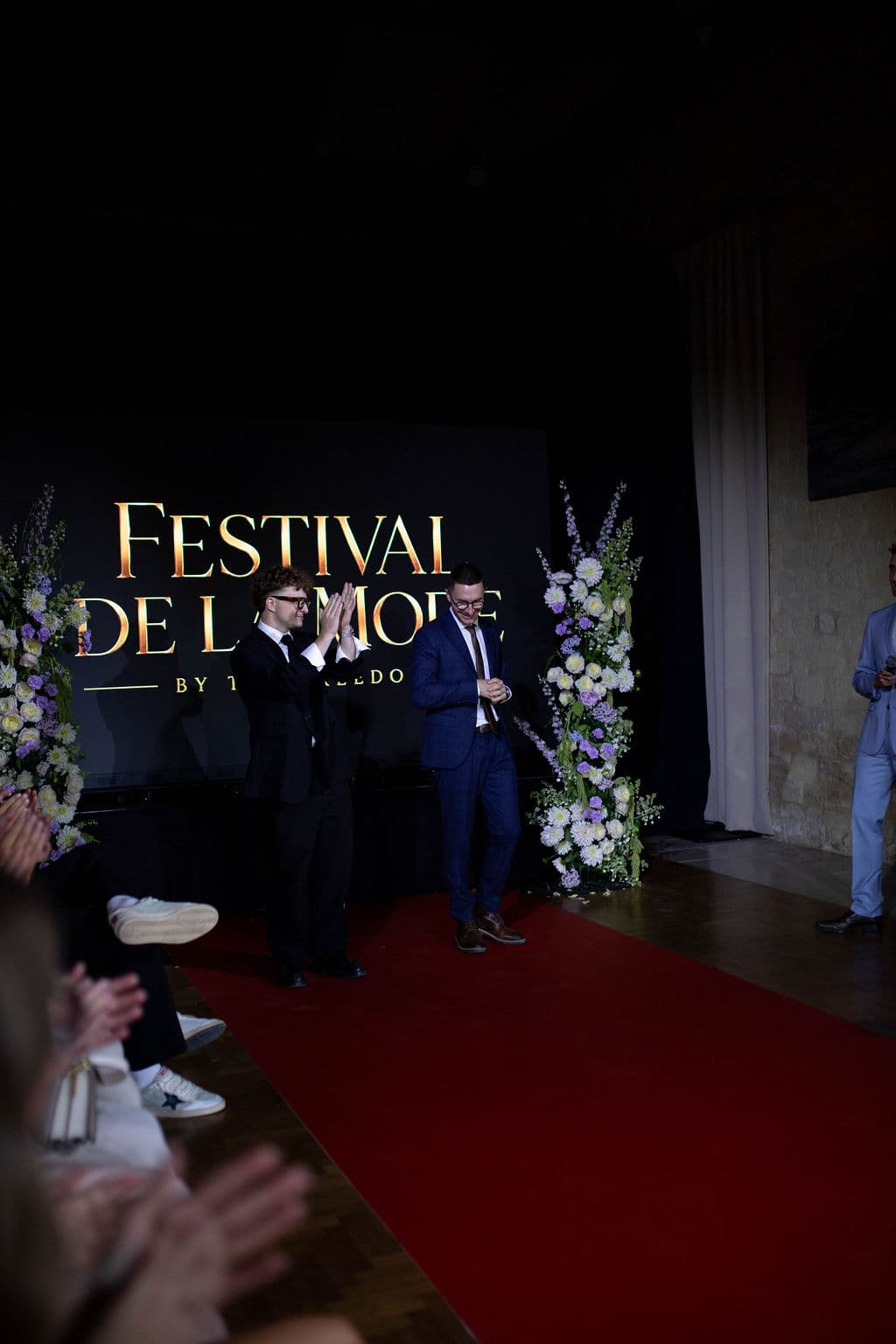 Clément Gouin et Esteban France sur la scène du Festival de la Mode de Caen, devant le tapis rouge et les compositions florales, au Domaine de la Cour des Lys