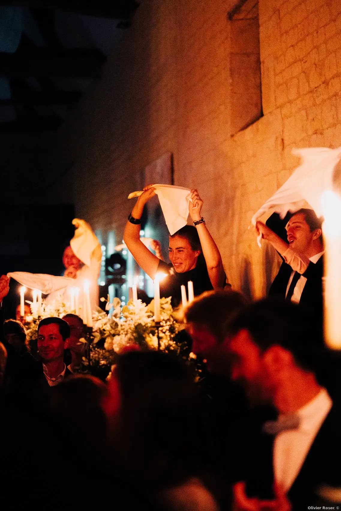 Dîner mariage Domaine de la Cour des Lys — invités agitant leurs serviettes blanches lors d'une chanson, bougies et candélabres sur la grande tablée