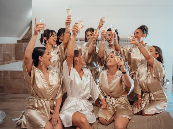 Les demoiselles d'honneur de Louise lèvent leur coupe en peignoirs satinés dorés — préparatifs du mariage au Domaine de la Cour des Lys